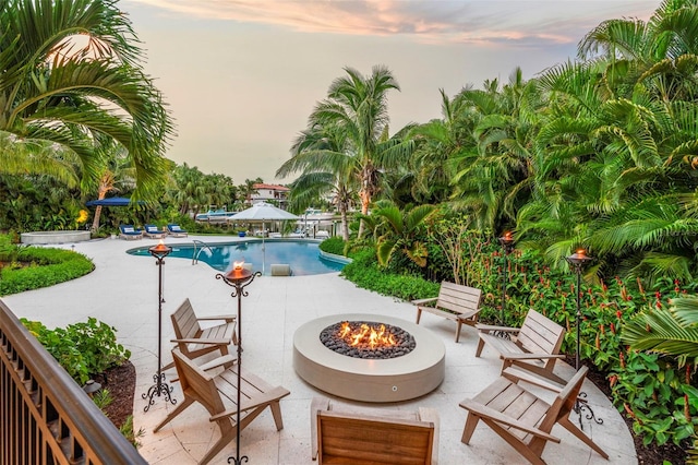 pool at dusk featuring a patio and an outdoor fire pit