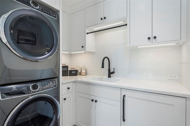 washroom featuring cabinets, stacked washer / drying machine, and sink