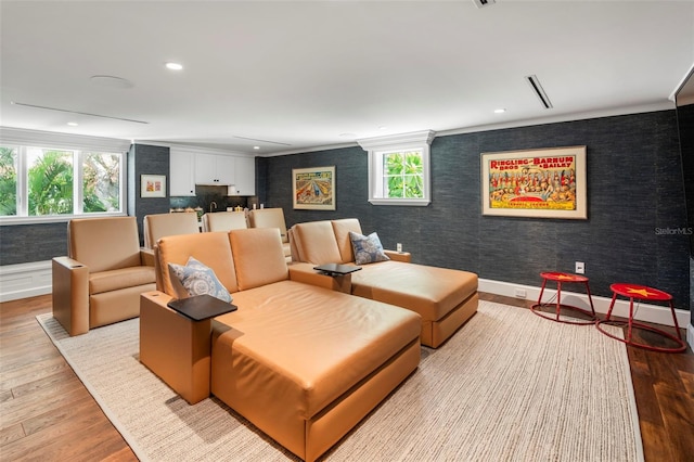 home theater with light wood-type flooring, a healthy amount of sunlight, and ornamental molding