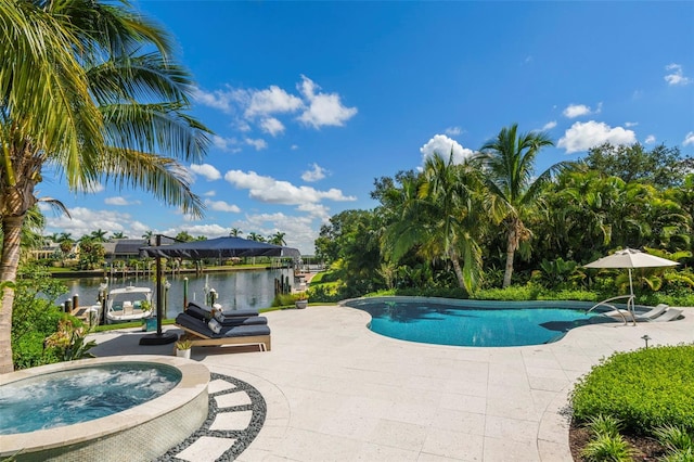 view of pool with an in ground hot tub, a water view, and a patio area