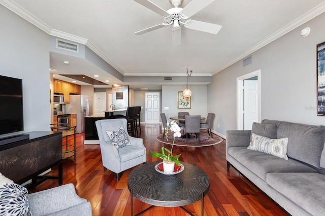 living room with ornamental molding, dark hardwood / wood-style flooring, and ceiling fan