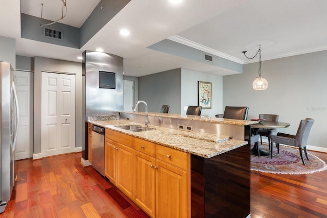 kitchen featuring dark wood-type flooring, sink, a kitchen bar, appliances with stainless steel finishes, and ornamental molding