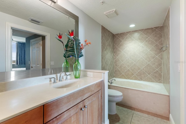 full bathroom featuring tiled shower / bath, vanity, a textured ceiling, tile patterned floors, and toilet