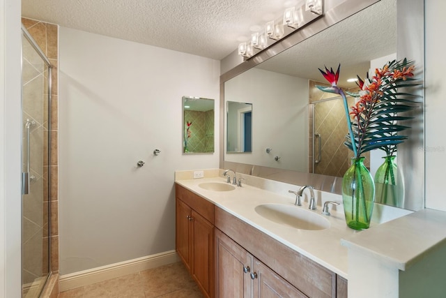 bathroom with a textured ceiling, tile patterned flooring, vanity, and a shower with shower door