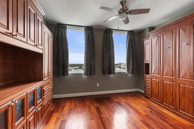 unfurnished bedroom with ceiling fan, dark hardwood / wood-style floors, and a textured ceiling