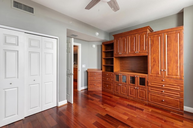 unfurnished living room featuring ceiling fan and dark wood-type flooring