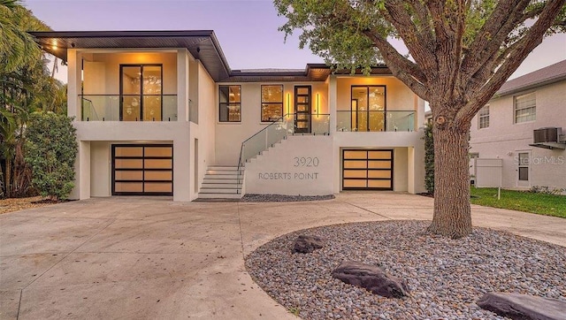 modern home featuring a garage, central air condition unit, and a balcony