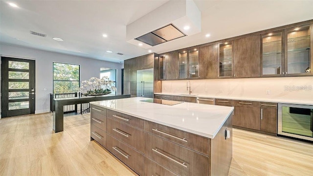 kitchen with wine cooler, a kitchen island, light wood-type flooring, stainless steel dishwasher, and black electric cooktop