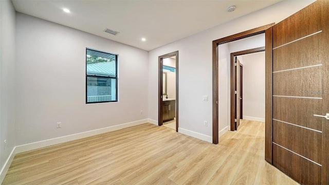 unfurnished bedroom with light hardwood / wood-style floors and ensuite bathroom