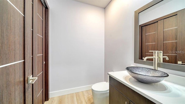 bathroom with hardwood / wood-style floors, vanity, and toilet