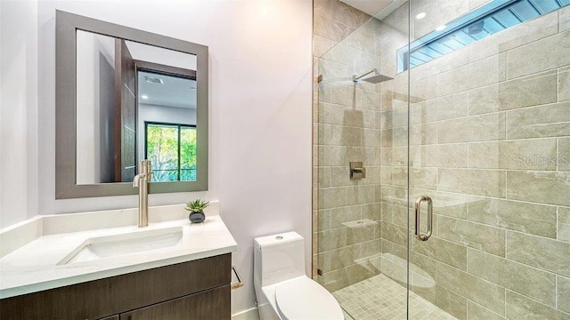 bathroom with toilet, vanity, and a shower with shower door