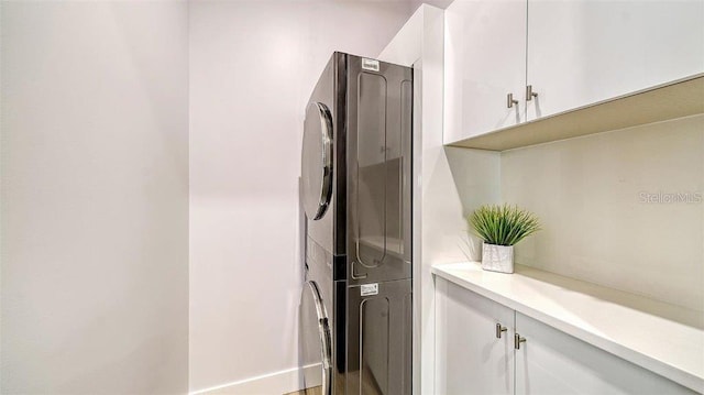 clothes washing area with cabinets and stacked washer / drying machine