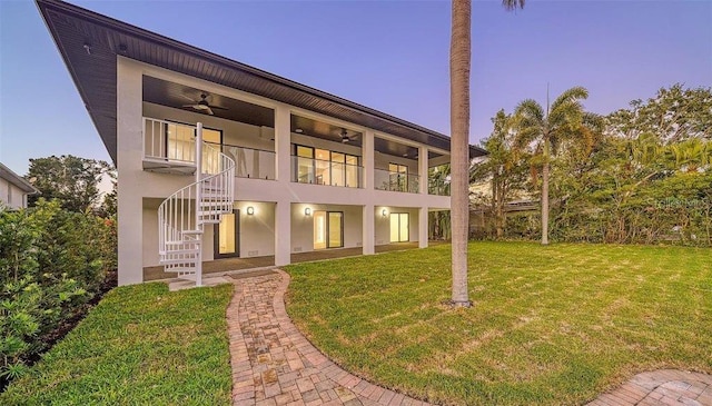 view of front of property with ceiling fan and a yard