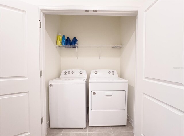 clothes washing area featuring light tile patterned floors and washer and clothes dryer