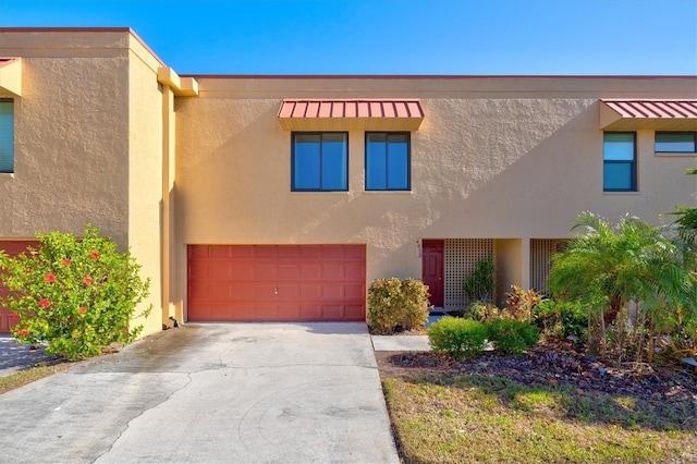view of front of home with concrete driveway, an attached garage, and stucco siding