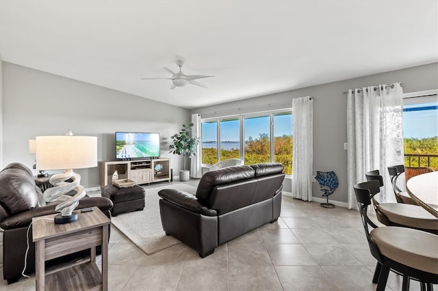 living area featuring a ceiling fan, baseboards, light tile patterned floors, and lofted ceiling