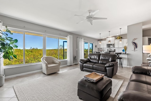 living room featuring baseboards, ceiling fan, and light tile patterned floors