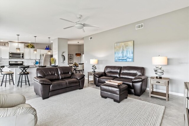 living area with visible vents, baseboards, ceiling fan, and light tile patterned floors