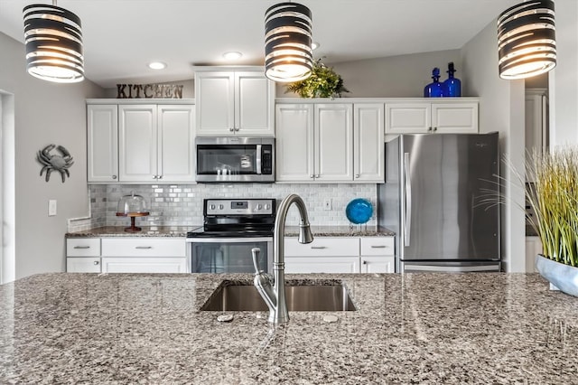 kitchen featuring backsplash, a sink, white cabinets, dark stone countertops, and stainless steel appliances