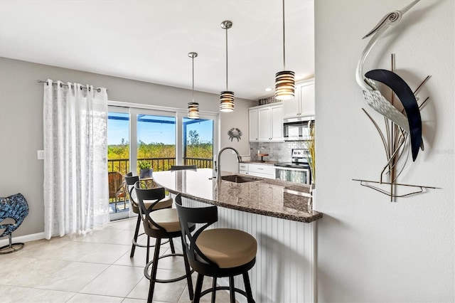 kitchen featuring backsplash, a sink, white cabinets, dark stone countertops, and stainless steel appliances