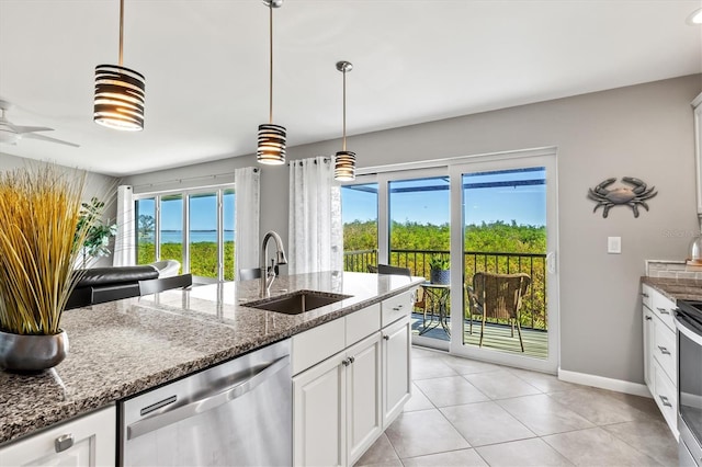 kitchen with white cabinets, a sink, dark stone countertops, stainless steel appliances, and baseboards