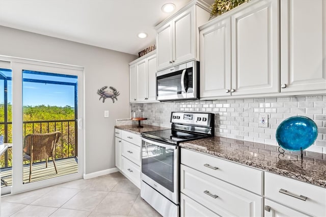 kitchen with appliances with stainless steel finishes, dark stone counters, baseboards, light tile patterned floors, and backsplash