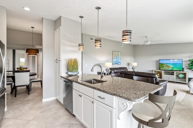 kitchen featuring stainless steel dishwasher, a ceiling fan, a peninsula, dark stone counters, and a sink