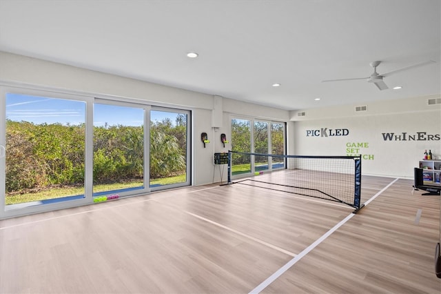 exercise room with ceiling fan and light hardwood / wood-style flooring