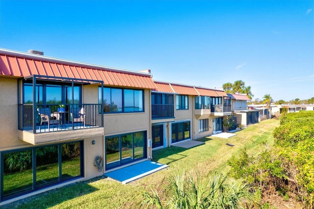 rear view of house featuring a balcony and a yard