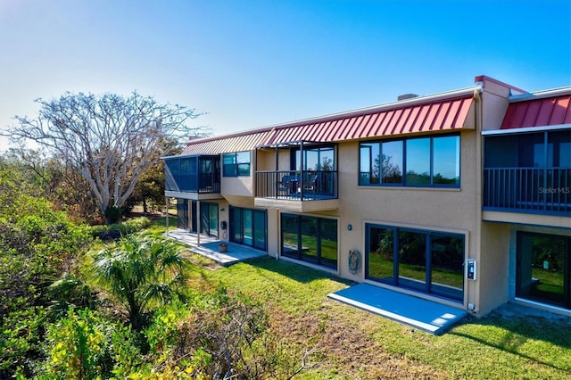 rear view of property with a lawn, stucco siding, and a patio