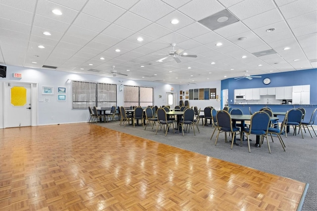 dining room with ceiling fan, light parquet flooring, and a drop ceiling