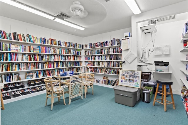 interior space with carpet, a ceiling fan, and bookshelves