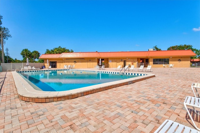 community pool with a patio and fence