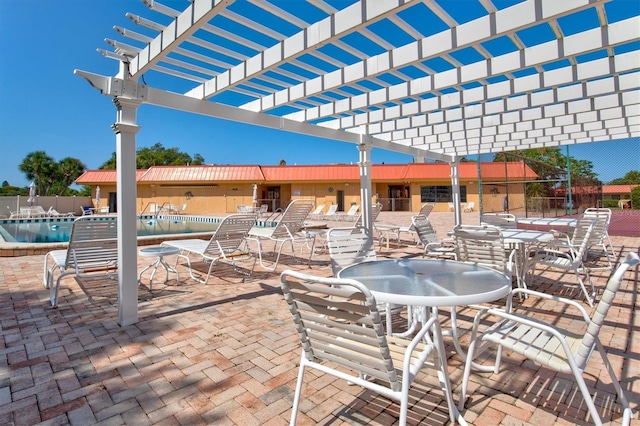 view of patio with a community pool, fence, and a pergola