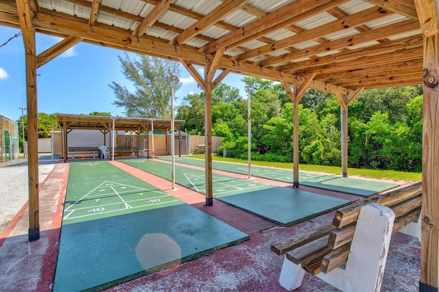 view of property's community with fence and shuffleboard