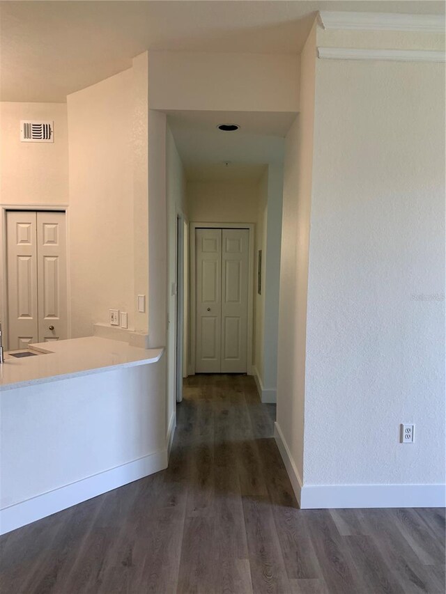 hall with visible vents, dark wood finished floors, and baseboards