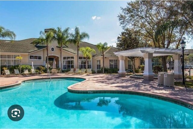 community pool with a patio area and a pergola