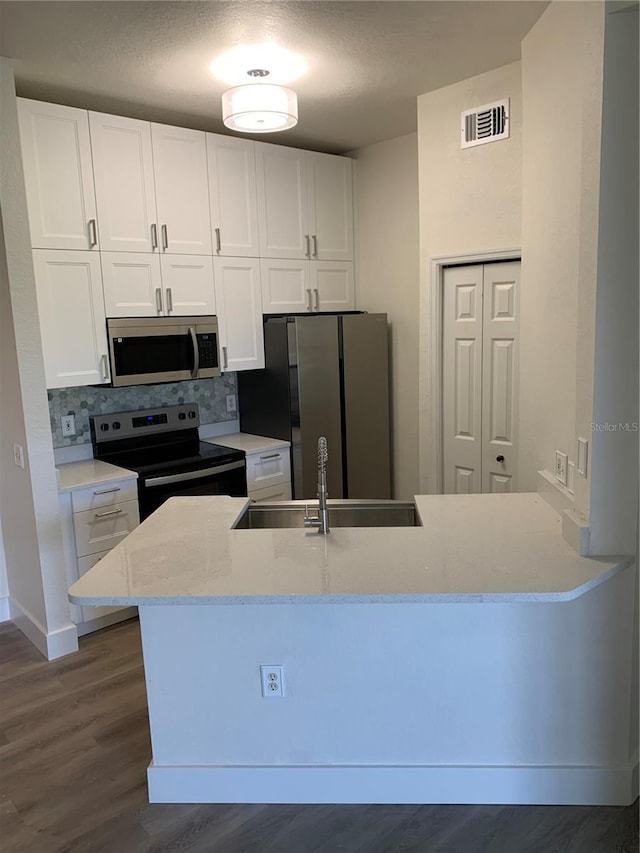 kitchen featuring stainless steel appliances, visible vents, backsplash, white cabinetry, and a sink