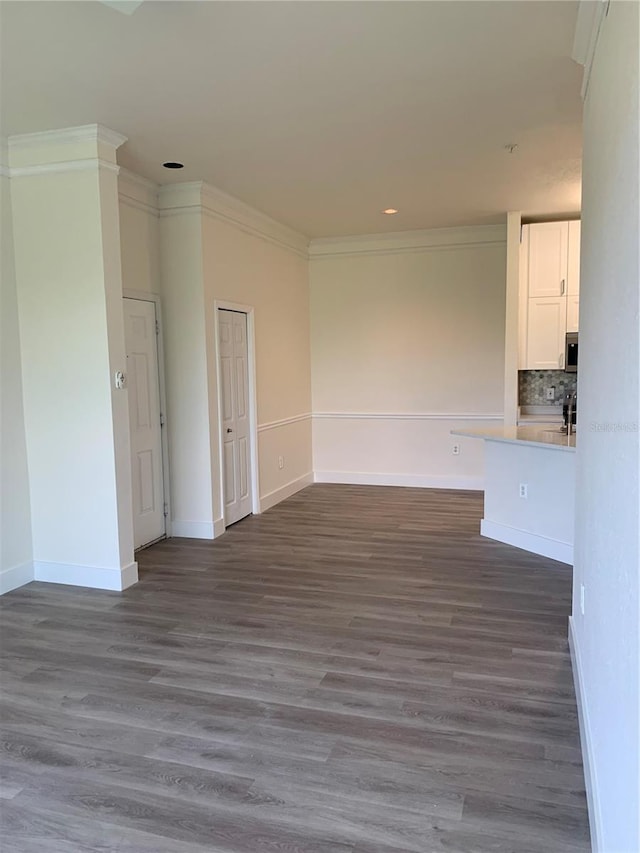 empty room with crown molding, dark wood finished floors, and baseboards