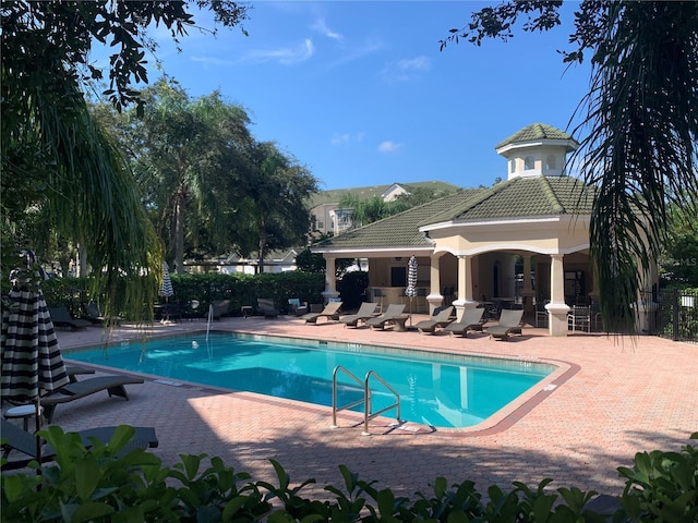 community pool with a patio area and fence