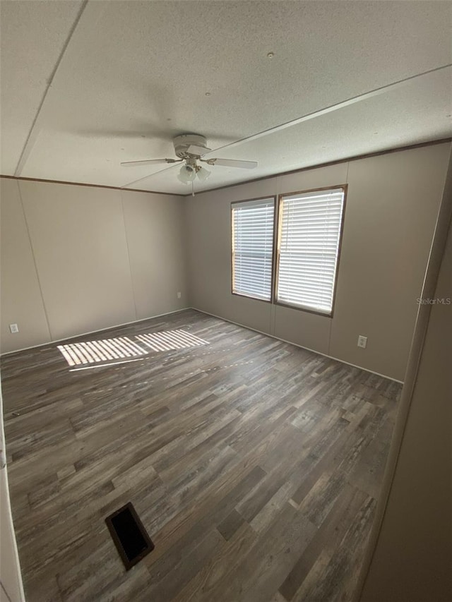 spare room with ceiling fan, a textured ceiling, and dark wood-type flooring