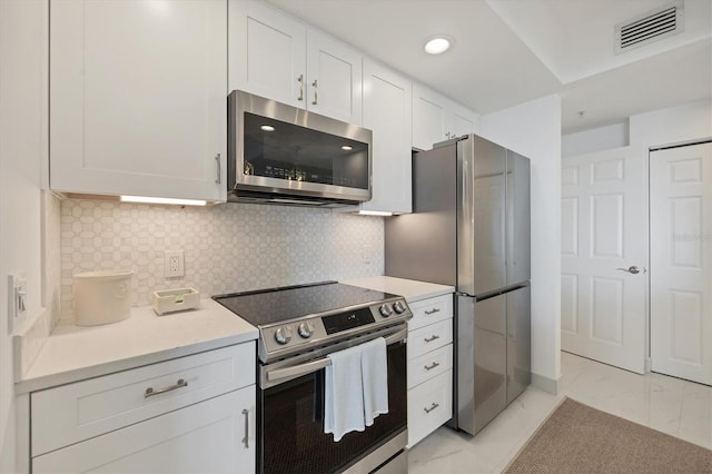 kitchen with tasteful backsplash, white cabinetry, and appliances with stainless steel finishes