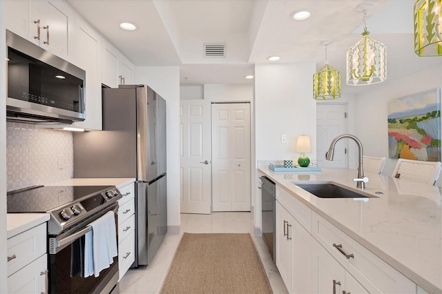 kitchen with pendant lighting, white cabinets, sink, light tile patterned floors, and stainless steel appliances