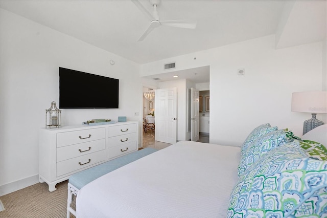 bedroom featuring light carpet, ensuite bathroom, and ceiling fan