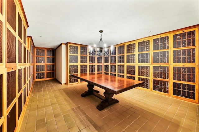 wine room with tile patterned flooring, a chandelier, and ornamental molding