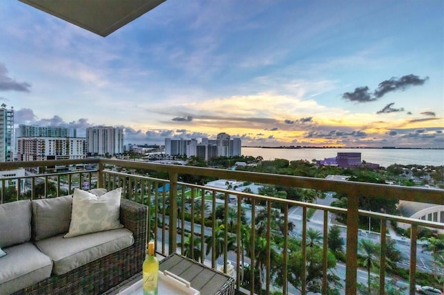 balcony at dusk with a water view and an outdoor hangout area