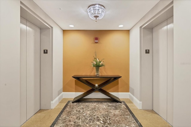 corridor featuring elevator and an inviting chandelier