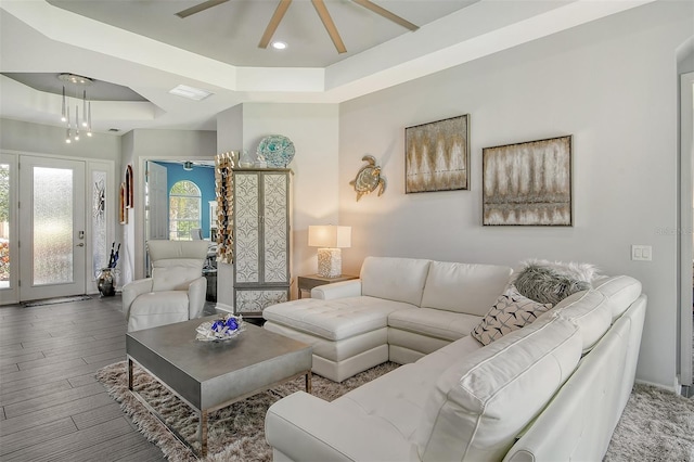 living room with a tray ceiling, ceiling fan, and hardwood / wood-style flooring