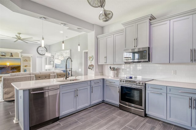 kitchen featuring hanging light fixtures, sink, dark hardwood / wood-style floors, appliances with stainless steel finishes, and kitchen peninsula