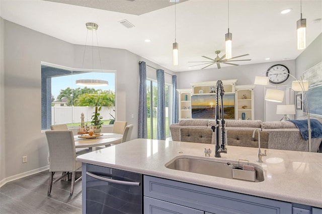 kitchen with ceiling fan, sink, hanging light fixtures, and wood-type flooring